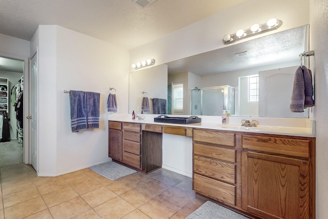 bathroom featuring tile patterned floors, vanity, a shower with shower door, and a textured ceiling