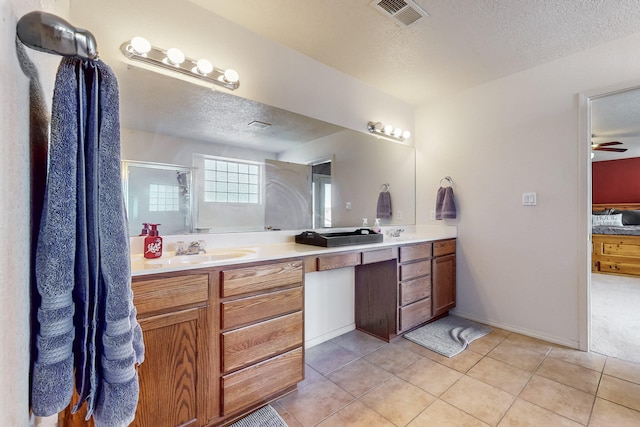 bathroom featuring tile patterned flooring, vanity, a textured ceiling, and an enclosed shower