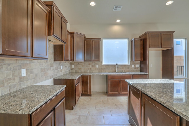 kitchen featuring a kitchen island, light stone countertops, sink, and tasteful backsplash