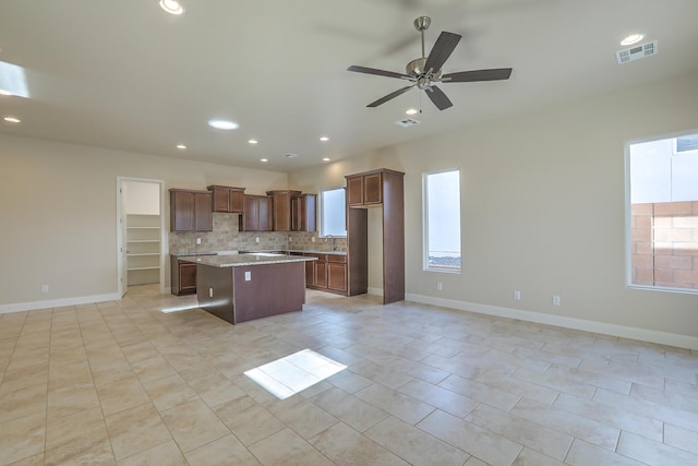 kitchen featuring ceiling fan, sink, light tile patterned floors, decorative backsplash, and a kitchen island