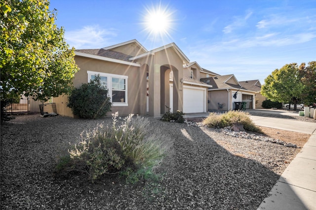 view of front of property featuring stucco siding, driveway, a garage, and fence