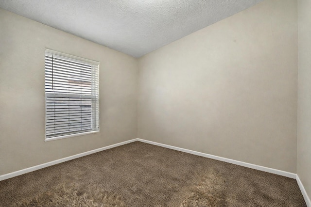 carpeted empty room with a textured ceiling and baseboards