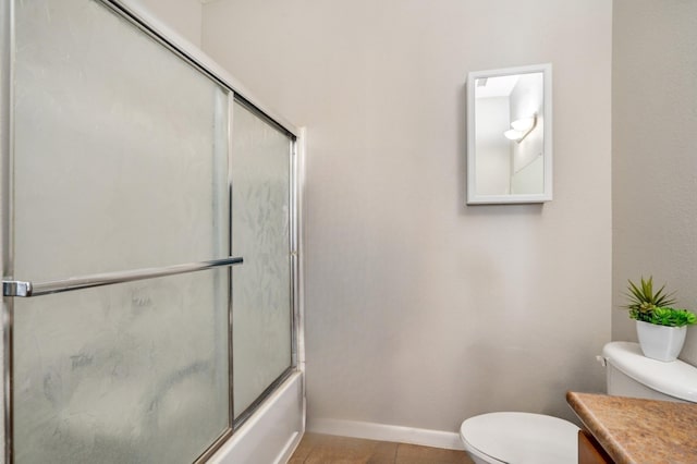 full bath with tile patterned floors, toilet, shower / bath combination with glass door, baseboards, and vanity