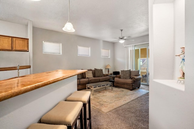 carpeted living room featuring ceiling fan and a textured ceiling