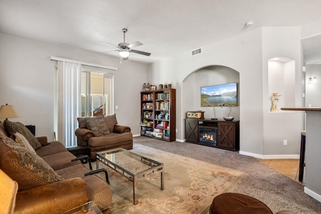 living room with a textured ceiling, ceiling fan, and light carpet