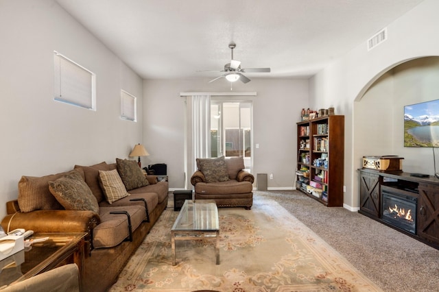 living area with visible vents, baseboards, carpet, and a ceiling fan