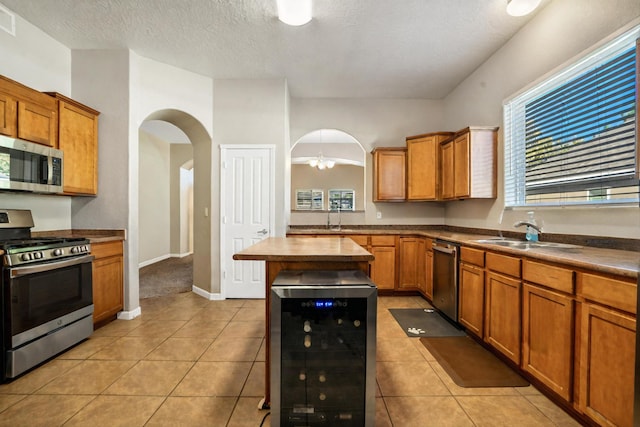 kitchen featuring light tile patterned floors, stainless steel appliances, wine cooler, and sink