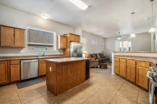 kitchen with ceiling fan, hanging light fixtures, stainless steel appliances, a textured ceiling, and a kitchen island