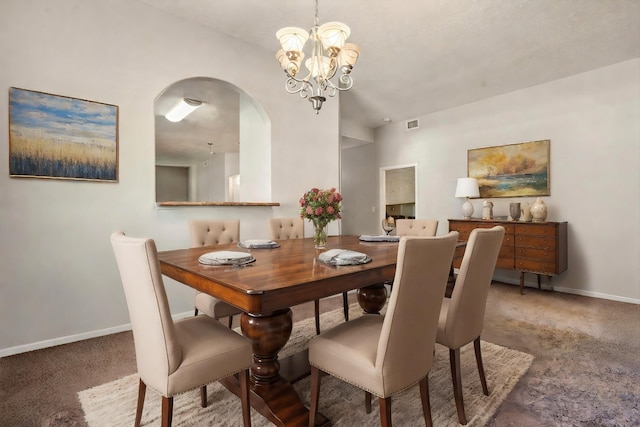 carpeted dining area with a chandelier