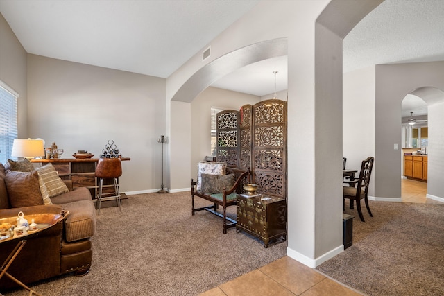 living area featuring arched walkways, visible vents, light colored carpet, and light tile patterned flooring