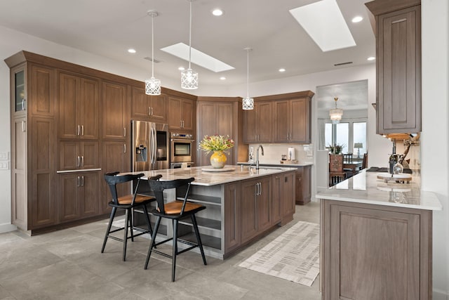 kitchen with a skylight, light stone countertops, and appliances with stainless steel finishes