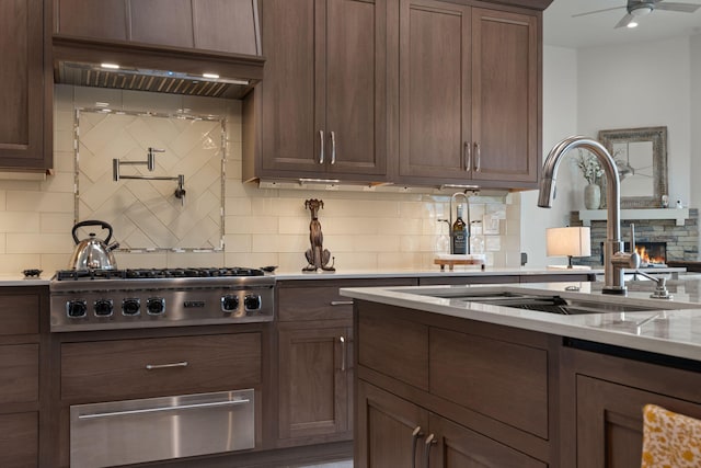 kitchen featuring backsplash, sink, custom range hood, and stainless steel gas stovetop