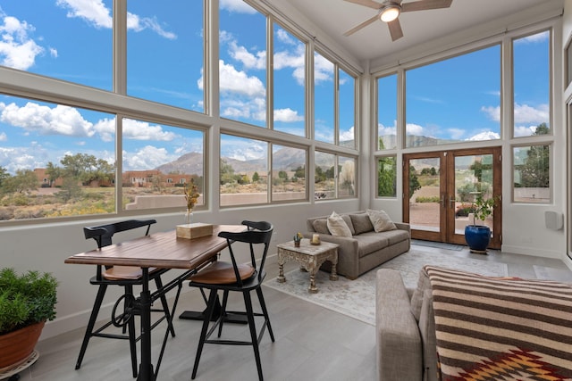 sunroom with a mountain view, french doors, plenty of natural light, and ceiling fan