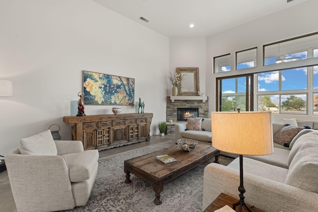 living room with a stone fireplace and a towering ceiling