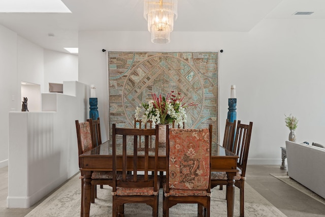 dining space featuring concrete flooring and a notable chandelier