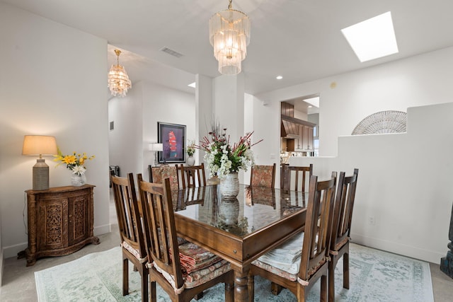 carpeted dining room featuring a skylight and a chandelier