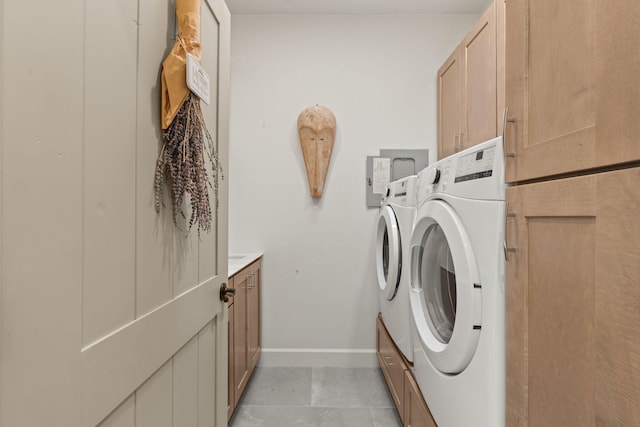 laundry area with washer and clothes dryer, light tile patterned flooring, and cabinets