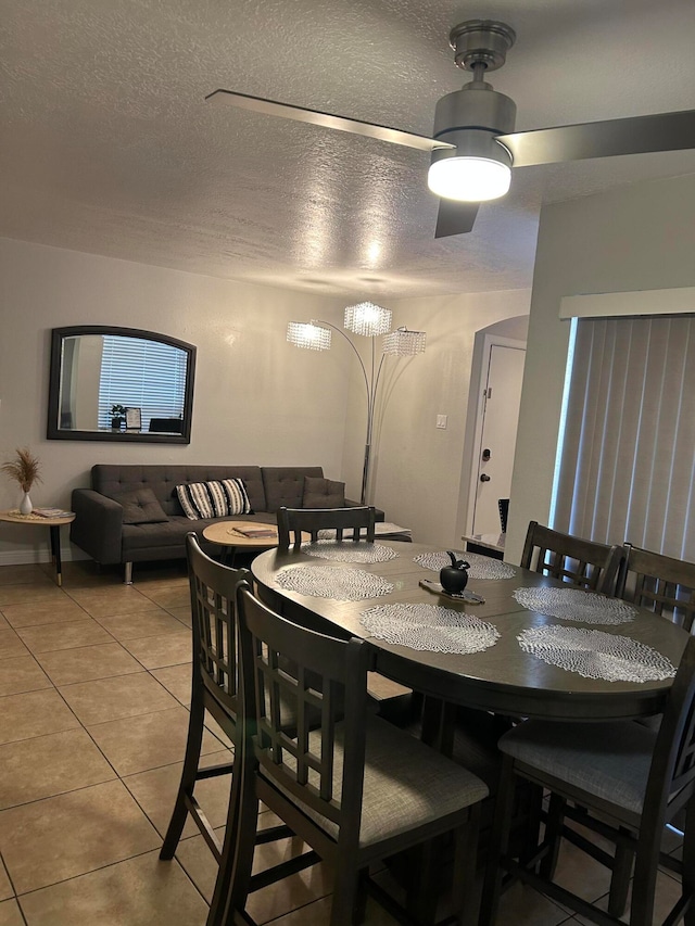 tiled dining room with ceiling fan and a textured ceiling