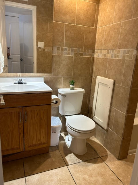 bathroom featuring tile walls, toilet, vanity, and tile patterned floors