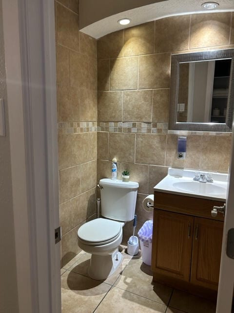 bathroom with toilet, vanity, tile walls, and tile patterned floors