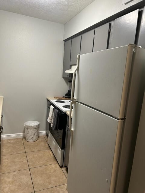 kitchen featuring a textured ceiling, light tile patterned flooring, white appliances, and range hood