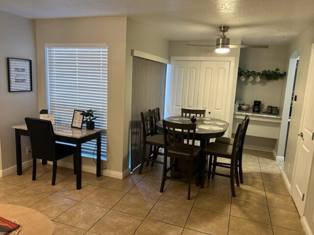 tiled dining space featuring a textured ceiling and ceiling fan