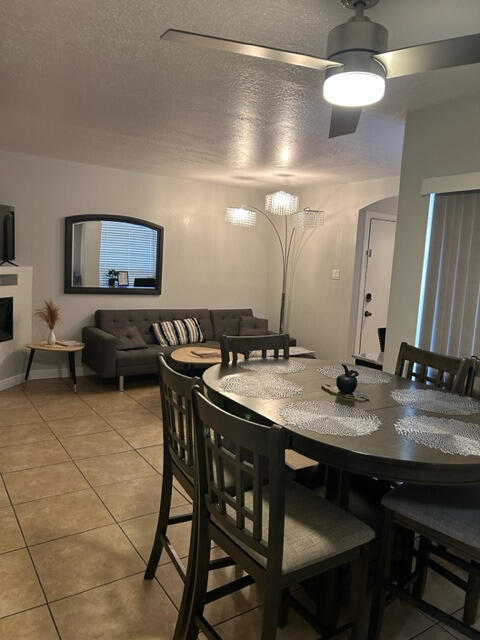 dining space with a textured ceiling, light tile patterned floors, and ceiling fan