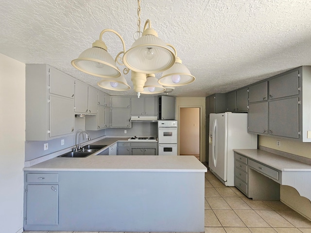 kitchen with white appliances, sink, kitchen peninsula, and hanging light fixtures