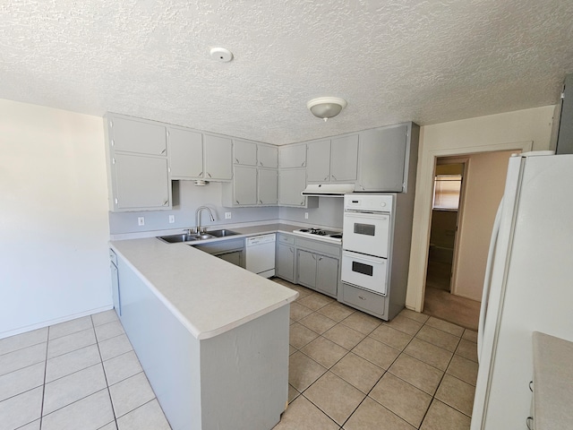 kitchen featuring sink, kitchen peninsula, a textured ceiling, white appliances, and light tile patterned flooring