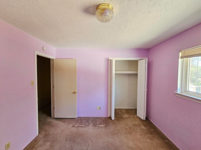 unfurnished bedroom with carpet, a textured ceiling, and a closet