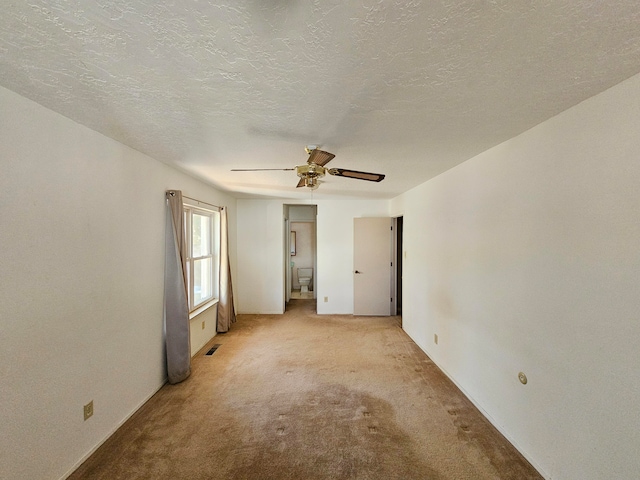 spare room with a textured ceiling, ceiling fan, and light carpet