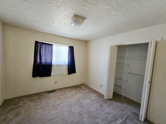 unfurnished bedroom with carpet floors, a textured ceiling, and a closet