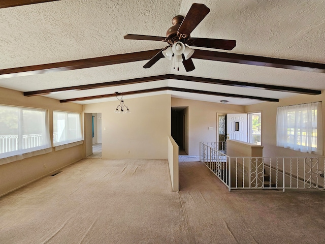 carpeted empty room with ceiling fan with notable chandelier, beam ceiling, and a textured ceiling