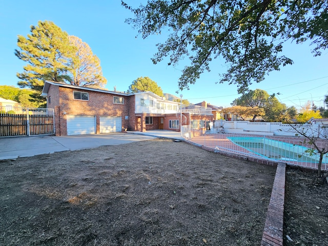 back of property featuring a garage and a fenced in pool