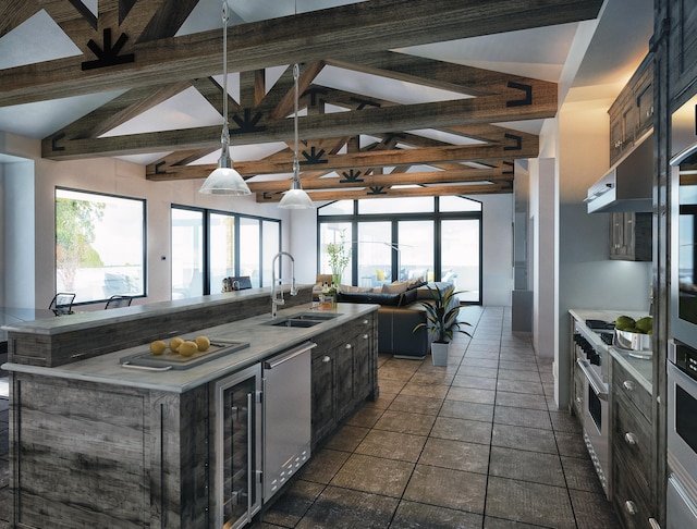 kitchen featuring a center island with sink, a healthy amount of sunlight, sink, lofted ceiling with beams, and appliances with stainless steel finishes