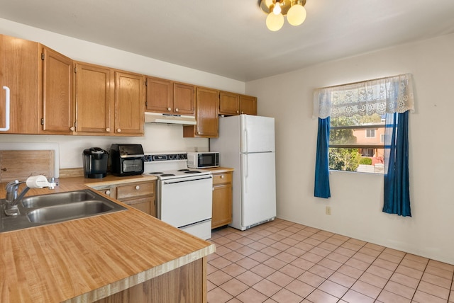 kitchen with light tile patterned floors, white appliances, and sink