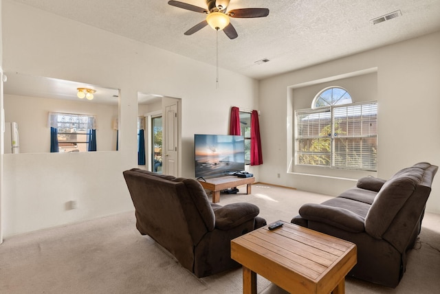 living room featuring a textured ceiling, light carpet, and ceiling fan