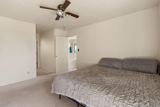 bedroom with a textured ceiling, light colored carpet, and ceiling fan