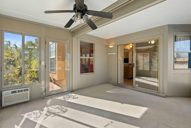 unfurnished sunroom featuring a wall mounted AC and ceiling fan