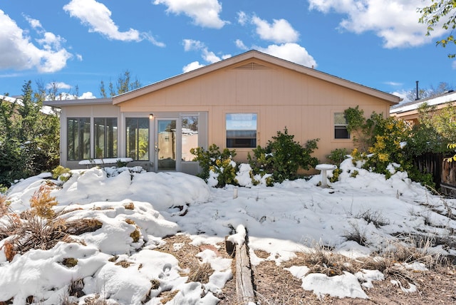 snow covered house featuring a sunroom