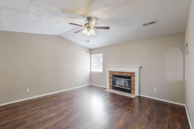 unfurnished living room featuring lofted ceiling, a textured ceiling, a tile fireplace, and dark hardwood / wood-style flooring