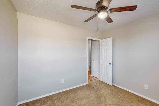 unfurnished room featuring ceiling fan, a textured ceiling, and light carpet