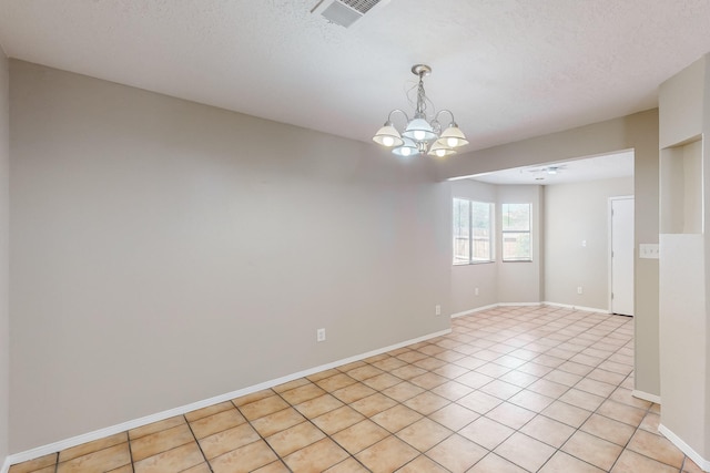 unfurnished room with a chandelier, a textured ceiling, and light tile patterned floors