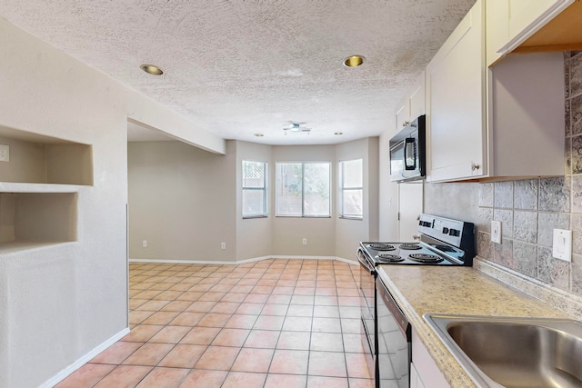 kitchen featuring white cabinets, decorative backsplash, appliances with stainless steel finishes, and light tile patterned flooring