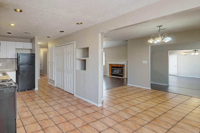 kitchen with white cabinetry, a tiled fireplace, black appliances, and light tile patterned floors