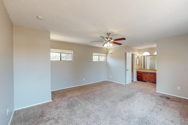 unfurnished room with a textured ceiling, light colored carpet, ceiling fan, and sink