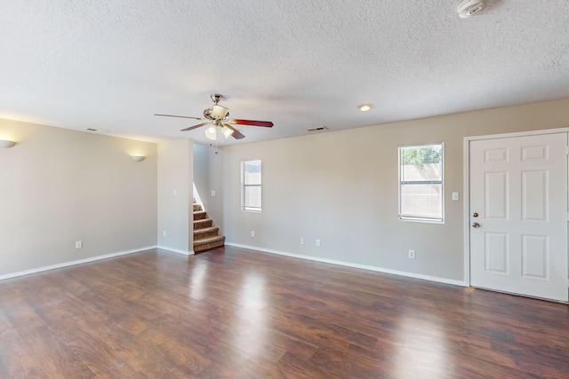 unfurnished living room featuring dark wood-type flooring, a textured ceiling, and ceiling fan