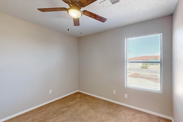 empty room featuring a textured ceiling, light colored carpet, and ceiling fan