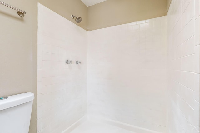 bathroom with a tile shower and toilet