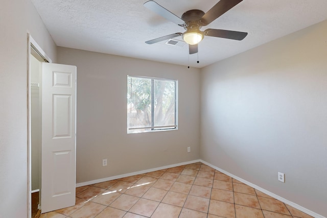 empty room featuring ceiling fan, a textured ceiling, and light tile patterned floors